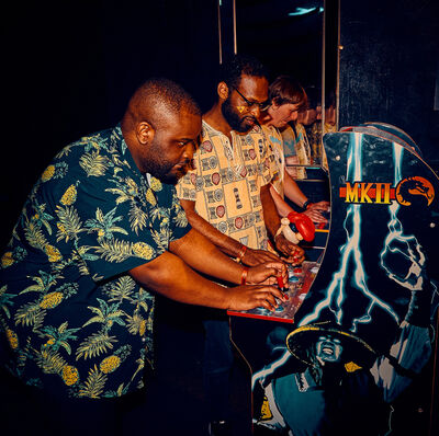 Three guys playing on an arcade game machine